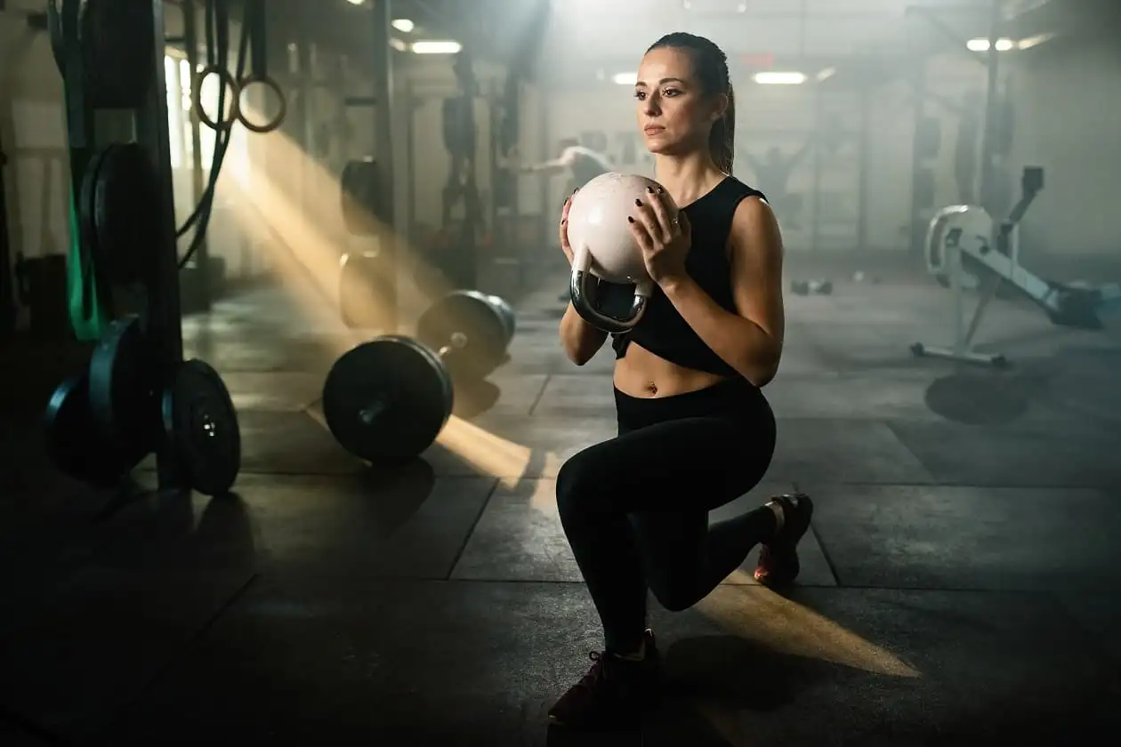 یک زن در حال تمرین با KettleBell در فضای باشگاه بانوان